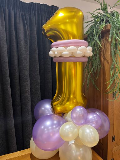 Gold number "1" balloon atop a cluster of purple and white balloons.