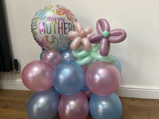 A balloon arrangement featuring a "Happy Mother" balloon and decorative flowers.
