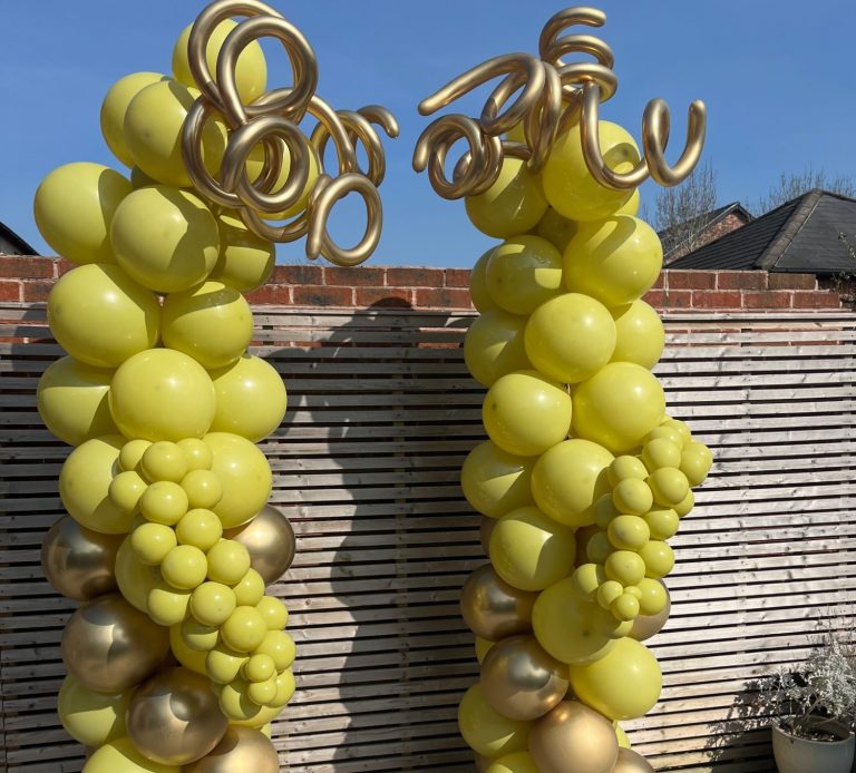Two large balloon clusters shaped like grapevines, with a sunny background.