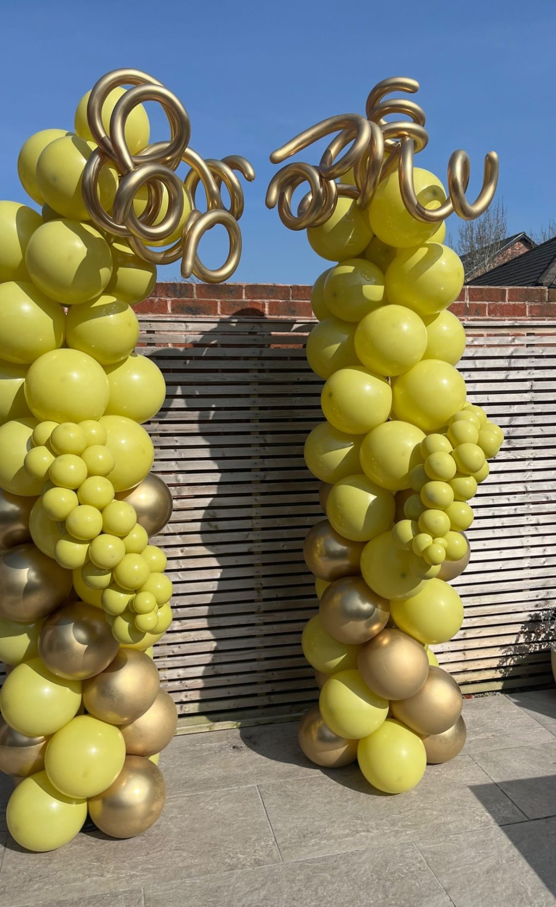 Two columns made of yellow and gold balloons, arching at the top.