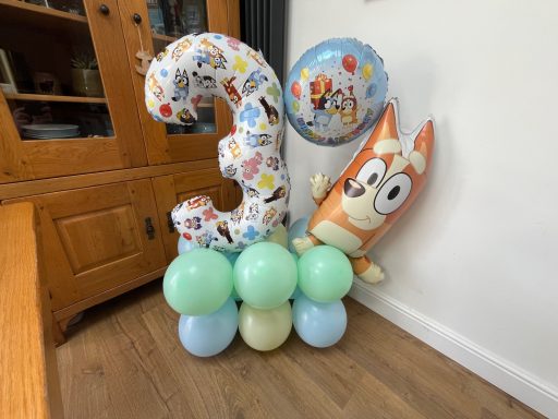Colourful party decorations featuring a large number 3, balloons, and a cartoon dog character.