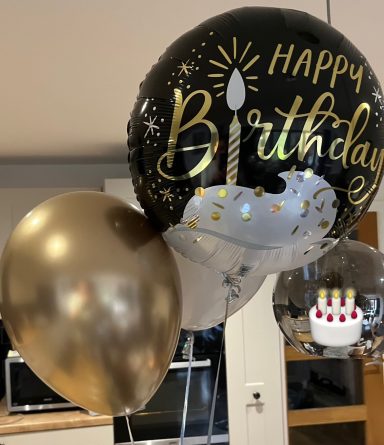 Black and gold birthday balloons with a candle design and a cake illustration.