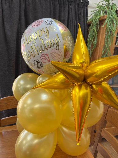 Gold balloons and a star decoration with a "Happy Birthday" balloon on top.